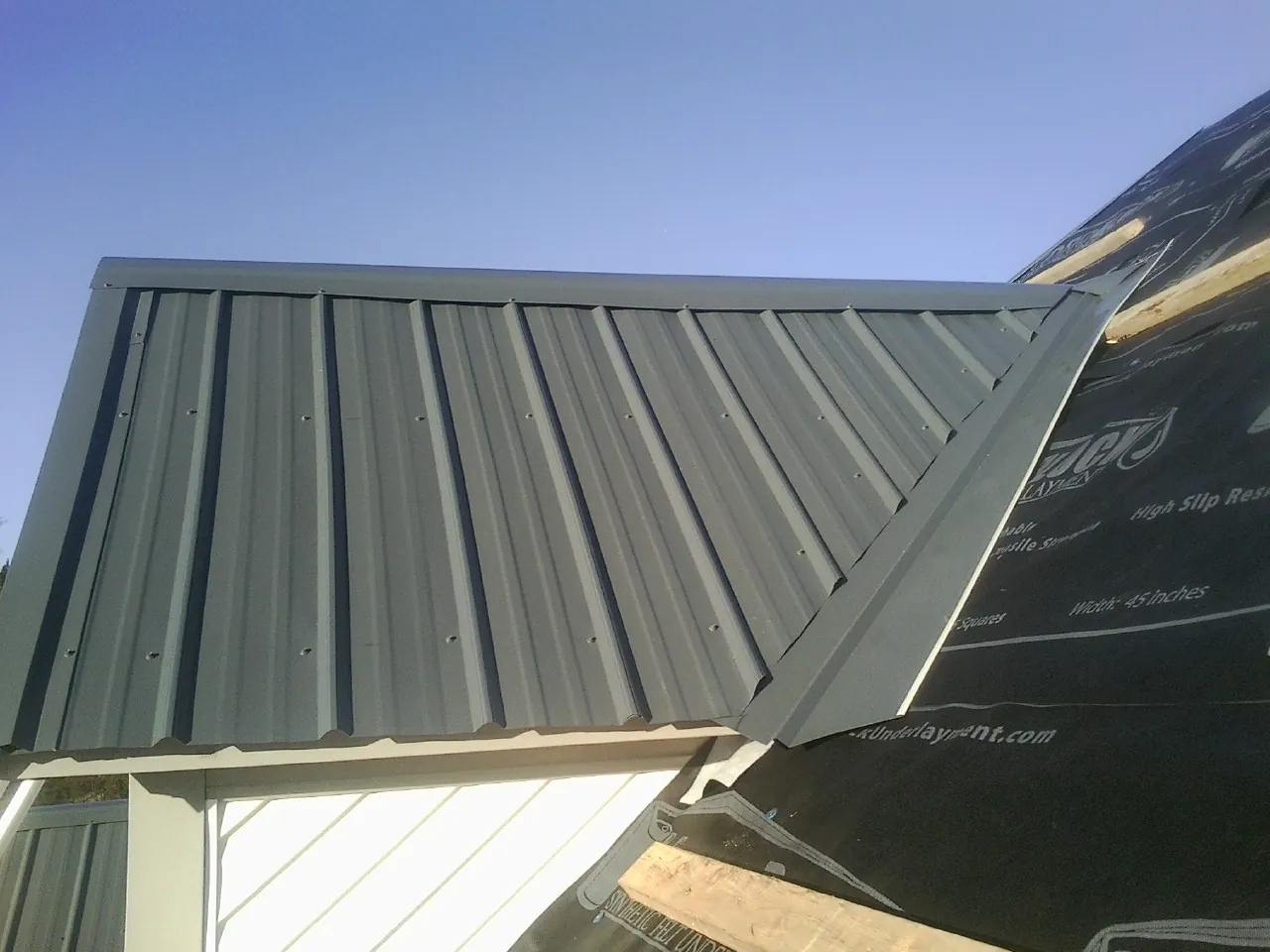 Gray metal roof panels going on over a garage gable in Eastchester