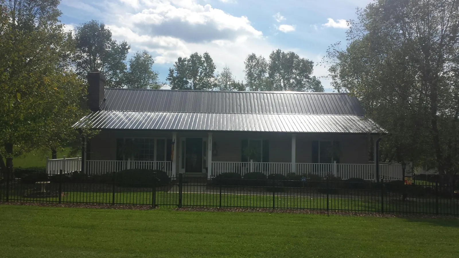 Gray metal roof on a brick ranch with a full width front porch — Gutter Guard Installation work by our crew in Eastchester