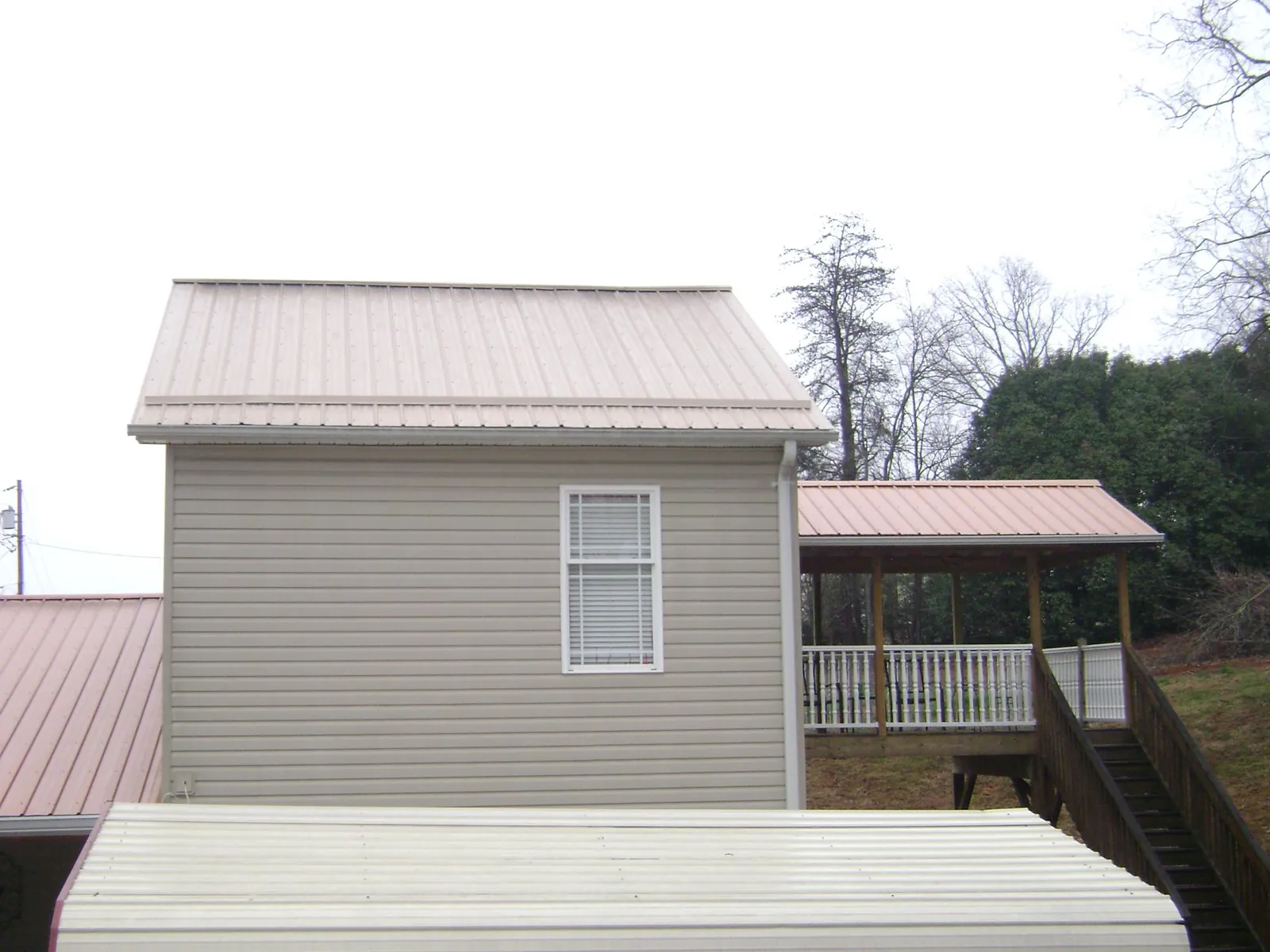 Tan metal roofs on a two story addition and attached porch, from a Roof Replacement job in Eastchester
