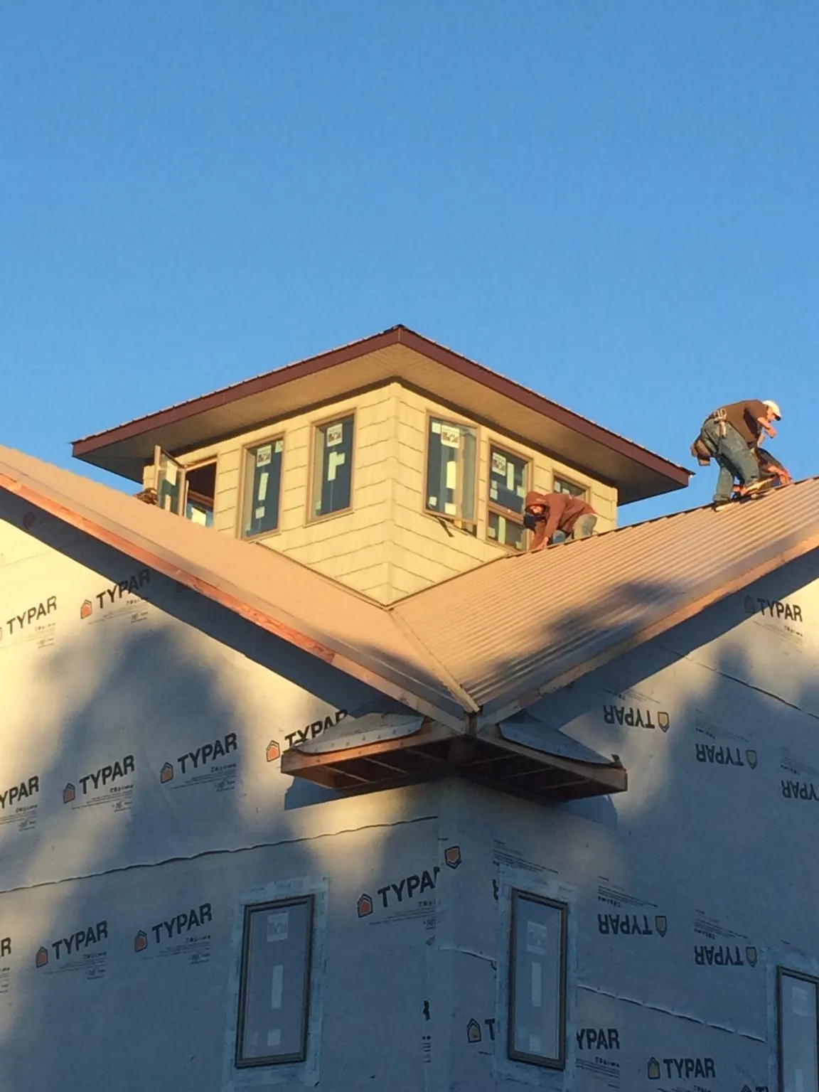 Roofers working around a rooftop cupola on a new metal roof at sunset — Roof Waterproofing in Eastchester by Roofing Brothers